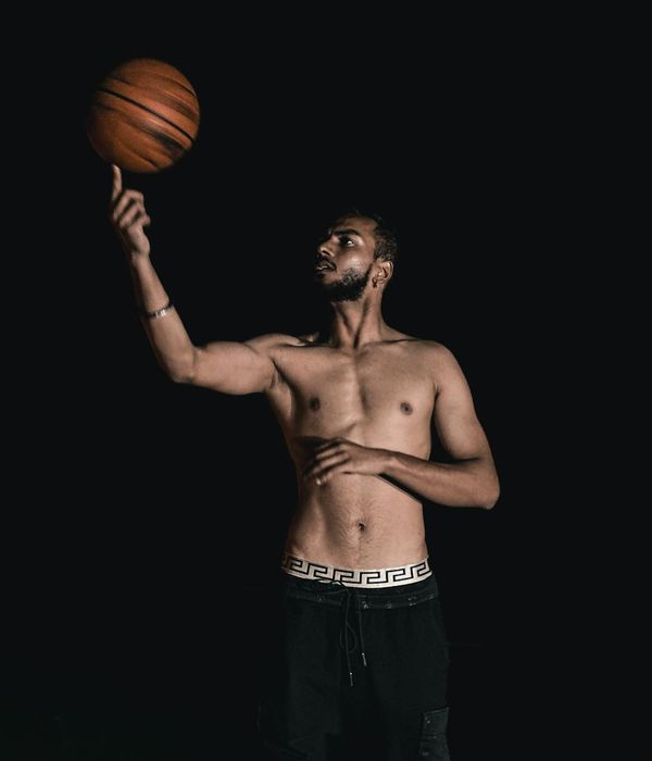 Athletic man performing a strength exercise in a dark studio setting.